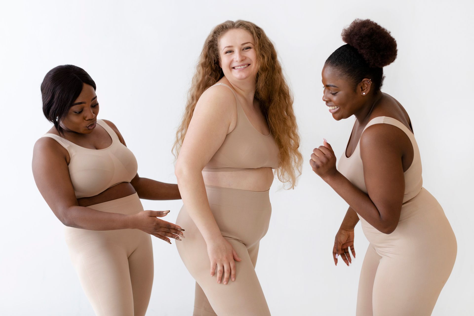 Three people in beige outfits smiling and interacting against a white background.