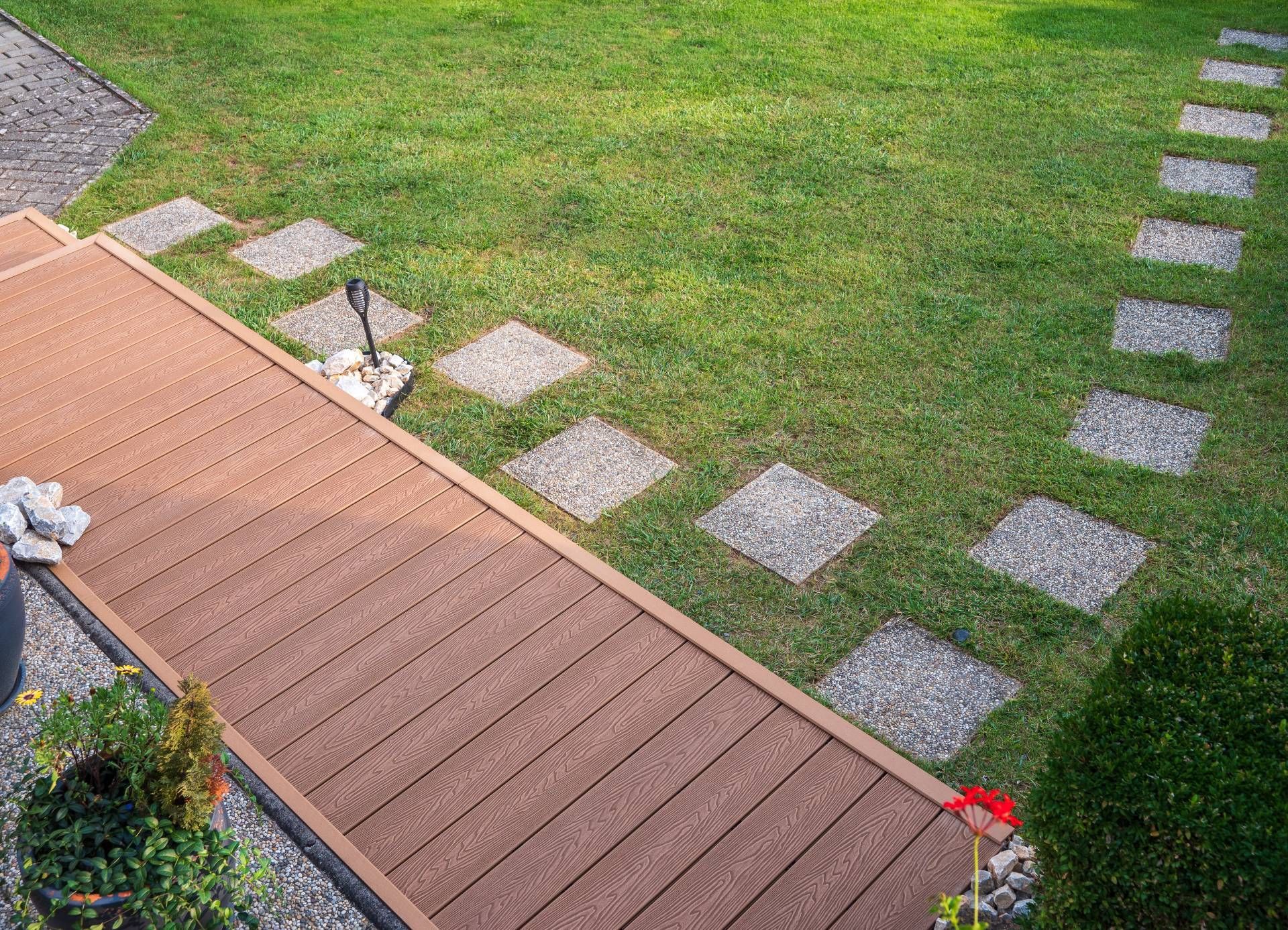 A bird's-eye view of a custom patio decking project in a yard with stepping stones