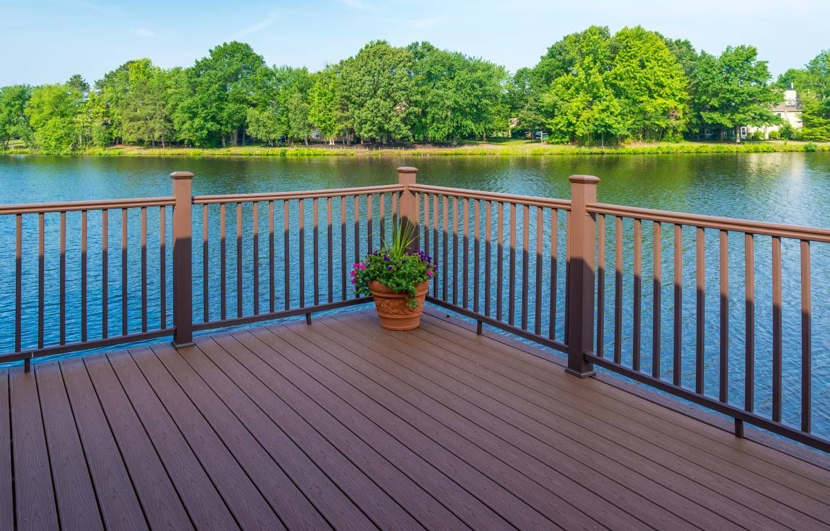 A brand-new custom deck with gorgeous dark stain and a curated flower pot, overlooking water
