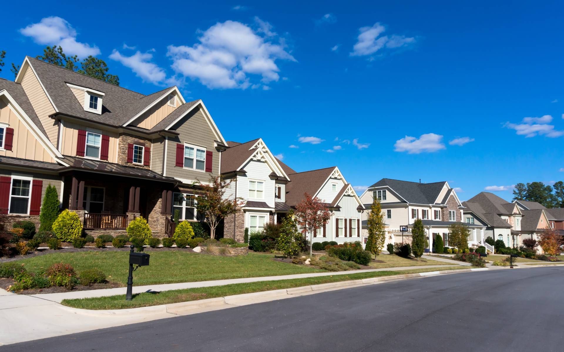 An image of several homes on the same street in a suburban neighborhood with blue skies
