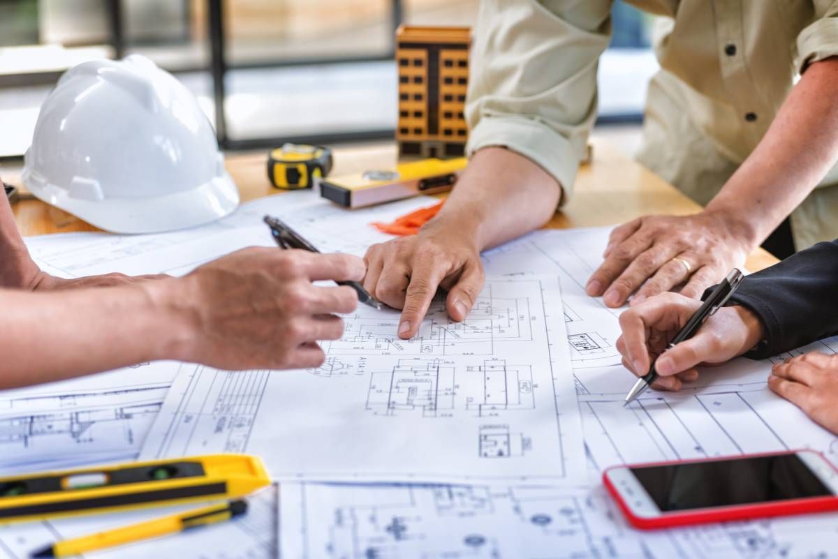 few members of a general contracting team meeting to go over project blueprints and plans