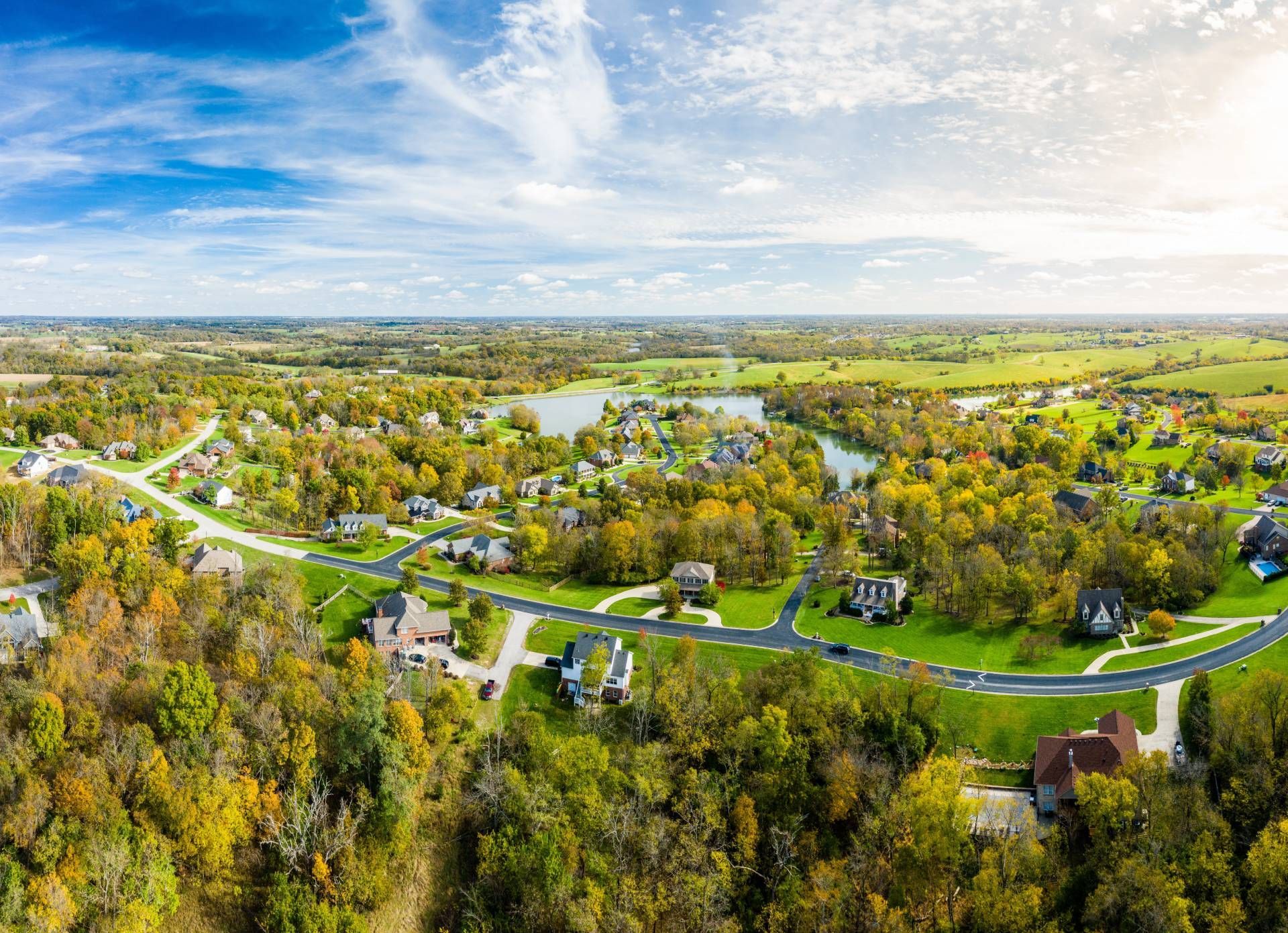 An aerial image of rural-like neighborhoods with changing tree foliage and blue skies near Georgetown, KY