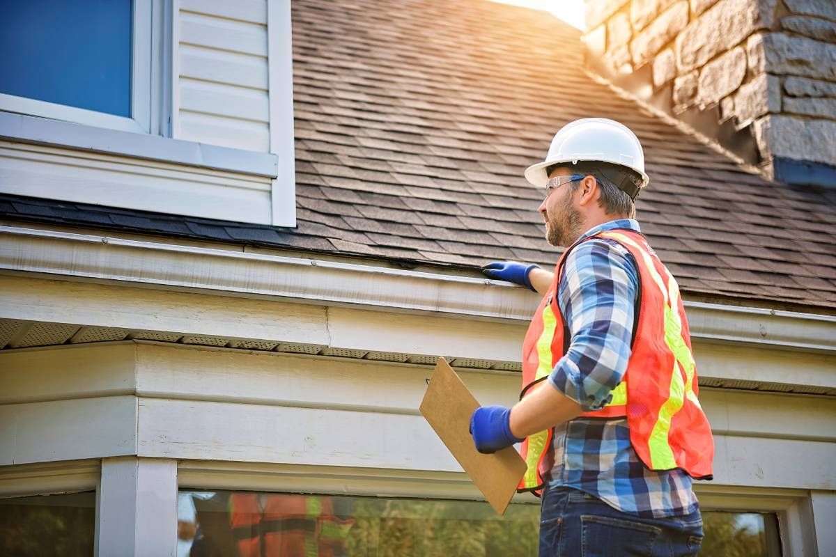 professional wearing a safety vest and a hard hat inspecting a new roofing project