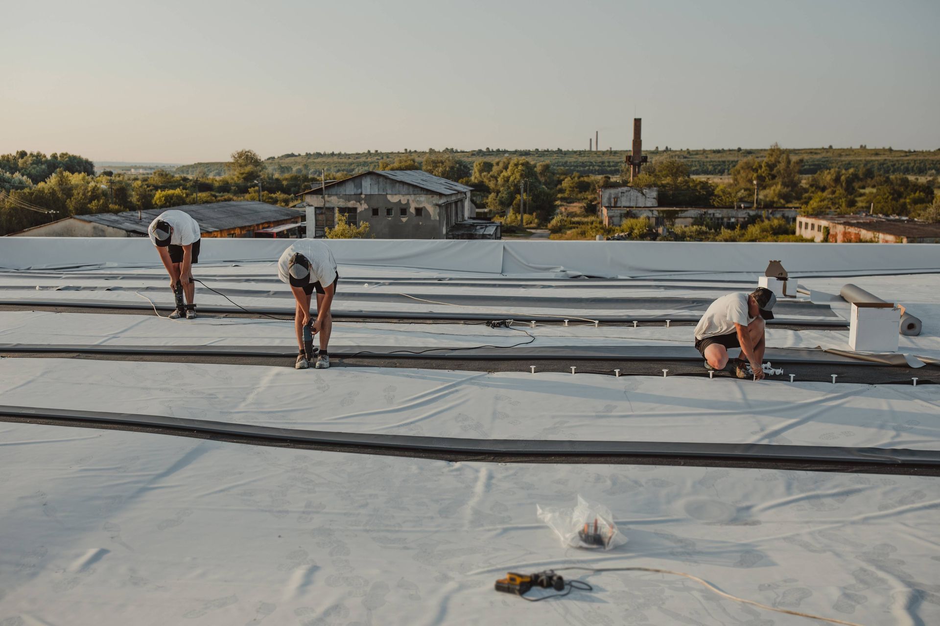 Roofing installers using drills to add a new roof to a commercial property