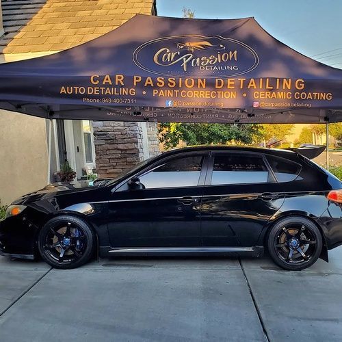 A black car is parked under a car passion detailing tent