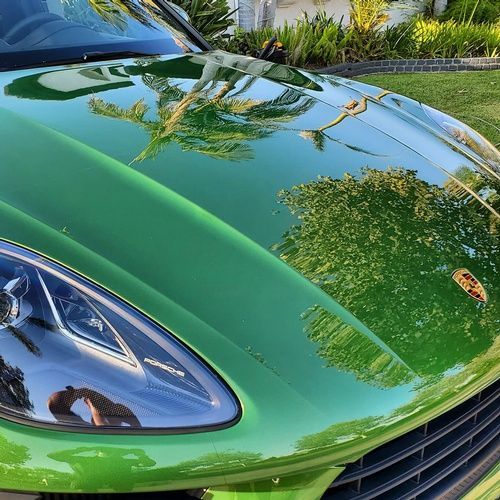 A green porsche macan turbo is parked in a driveway.