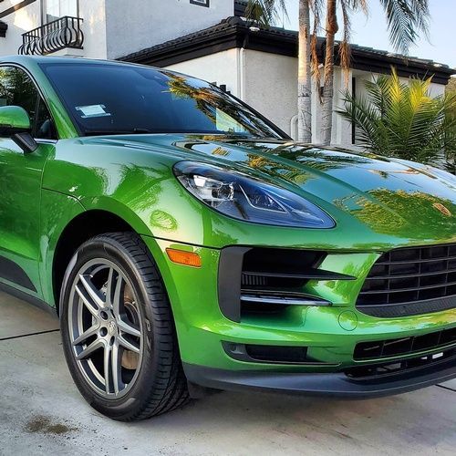 A green porsche macan is parked in front of a house