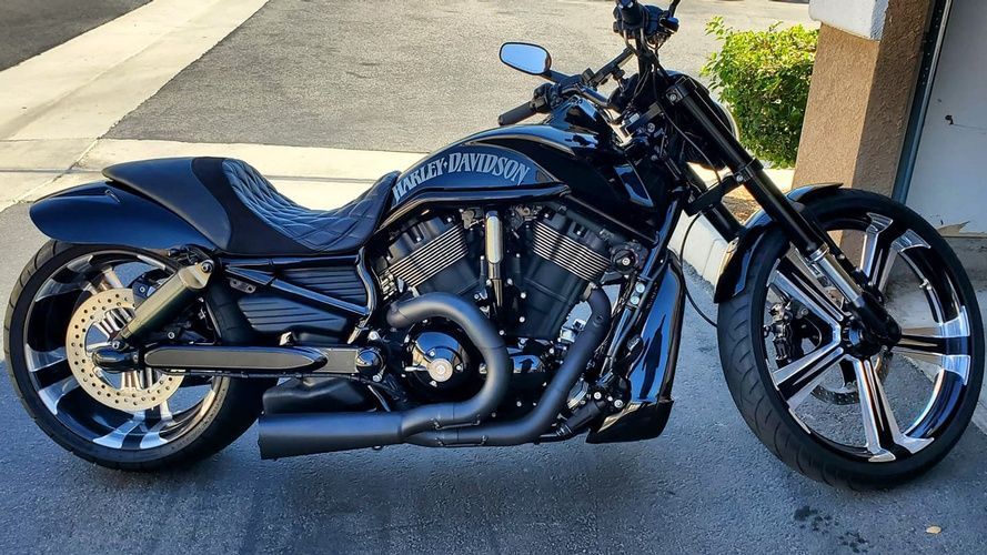 A black harley davidson motorcycle is parked in front of a garage.