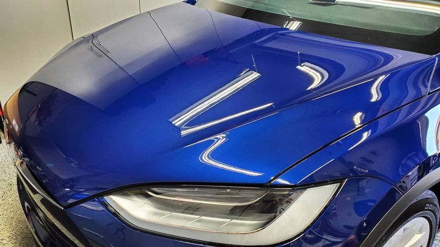 A blue tesla model x is parked in a garage.