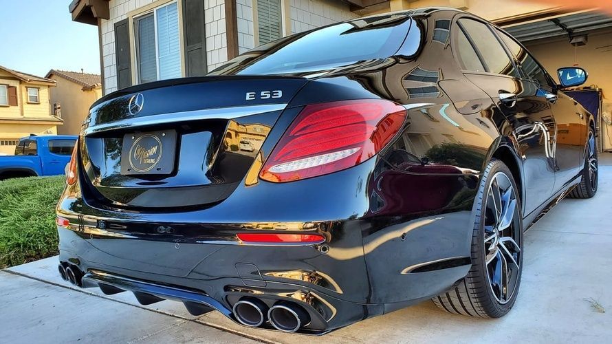 A black mercedes benz is parked in a driveway in front of a house.