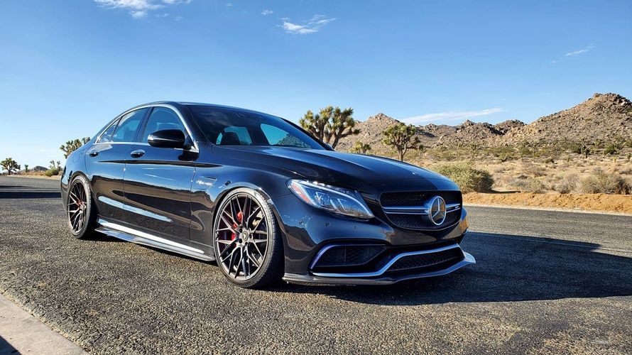 A black mercedes benz c63 amg is parked on the side of the road.
