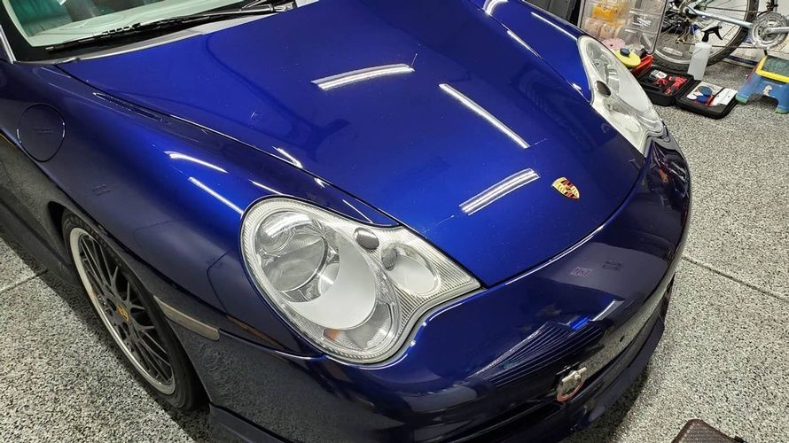 A blue porsche 911 is parked in a garage.