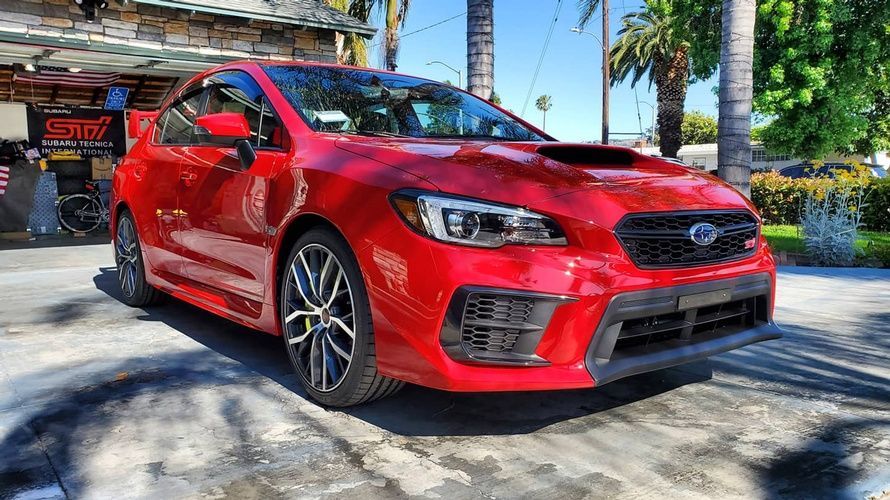 A red subaru wrx sti is parked in front of a garage.