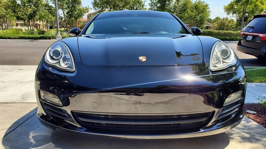 A black porsche panamera is parked in a driveway.