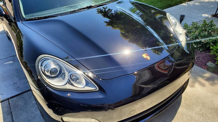 A black porsche panamera is parked in a driveway.