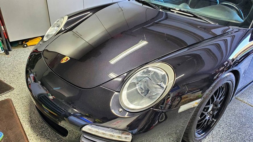 A black porsche 911 is parked in a garage.