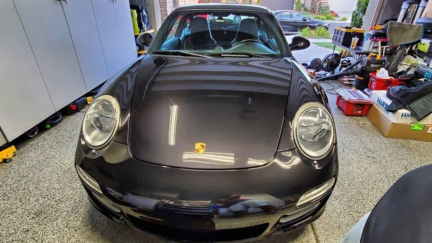 A black porsche 911 is parked in a garage.