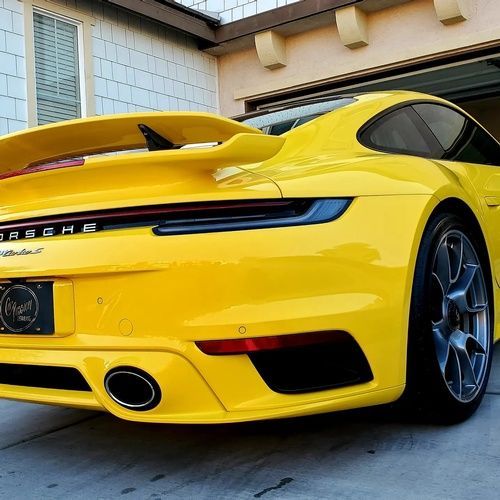 A yellow porsche is parked in front of a garage