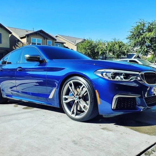 A blue bmw is parked in a driveway in front of a house.
