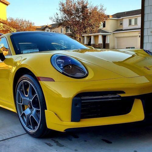 A yellow sports car is parked in front of a house.