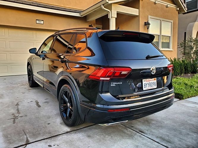A black volkswagen tiguan is parked in front of a house.