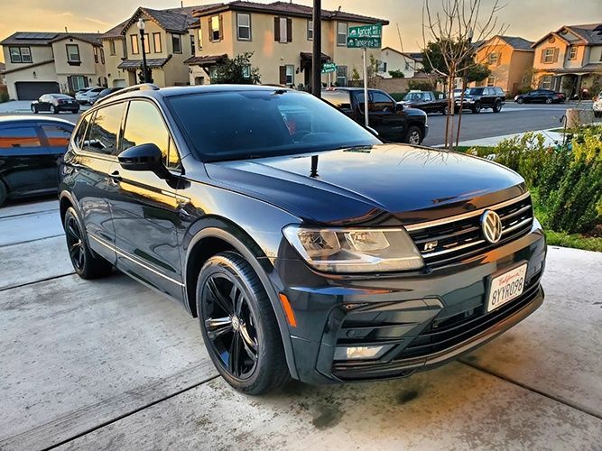A black volkswagen tiguan is parked in a driveway.