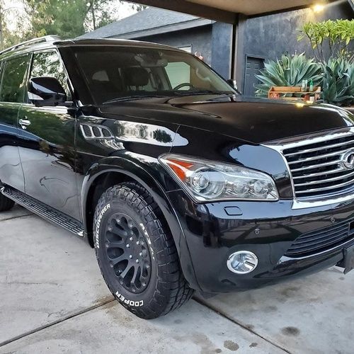 A black suv is parked in a driveway in front of a house.