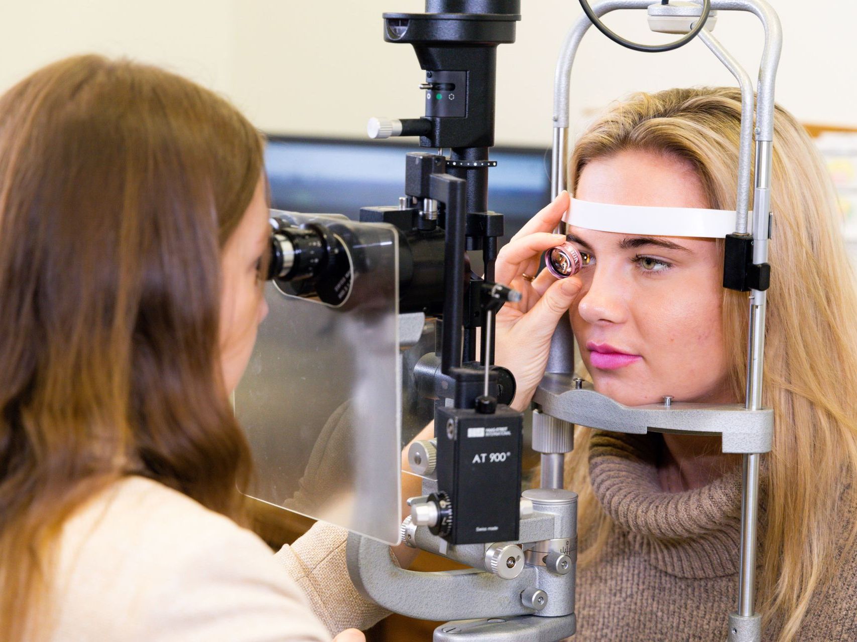 An image of a woman is getting her eyes examined by an ophthalmologist