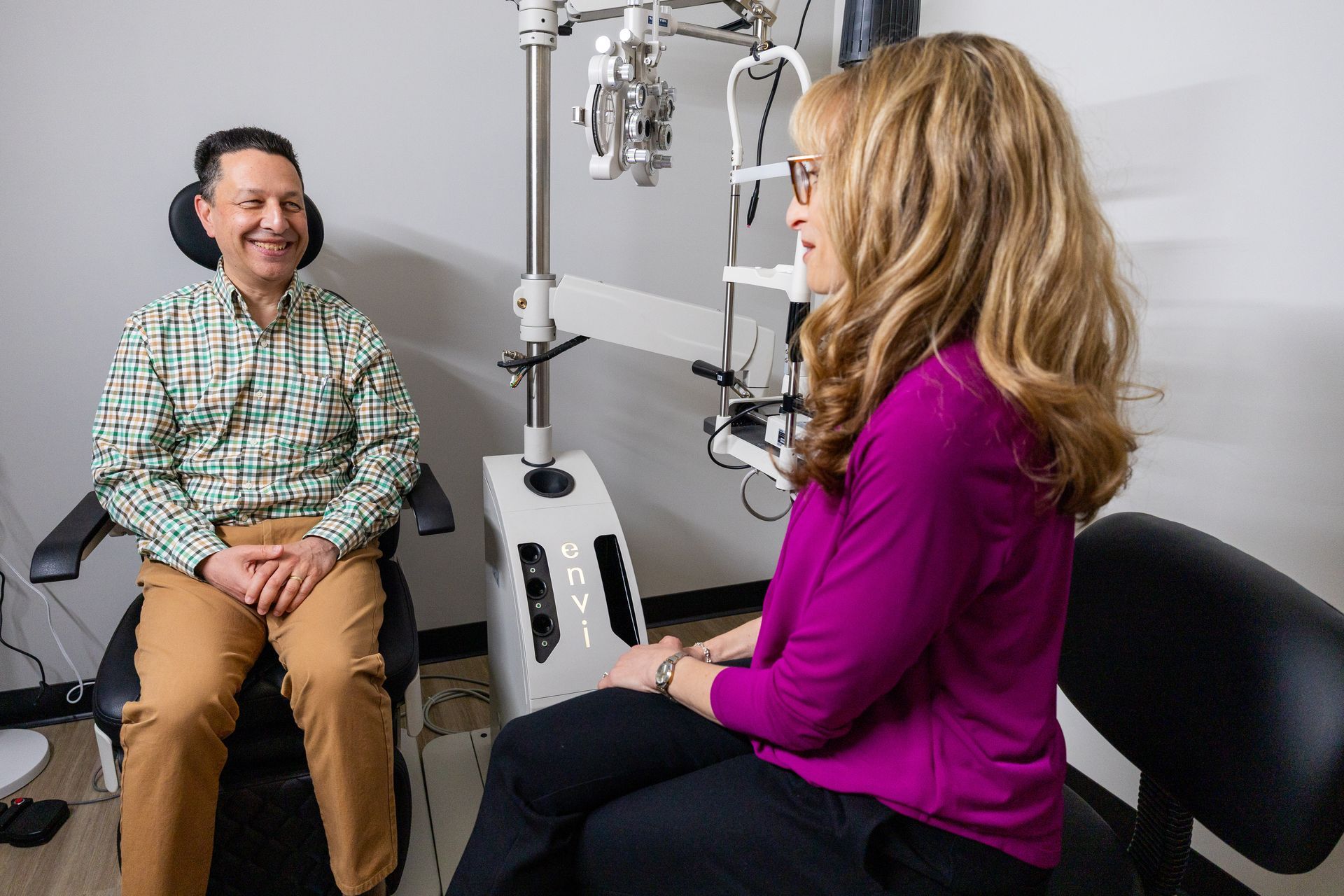 Two people talking in a medical office beside an eye exam machine