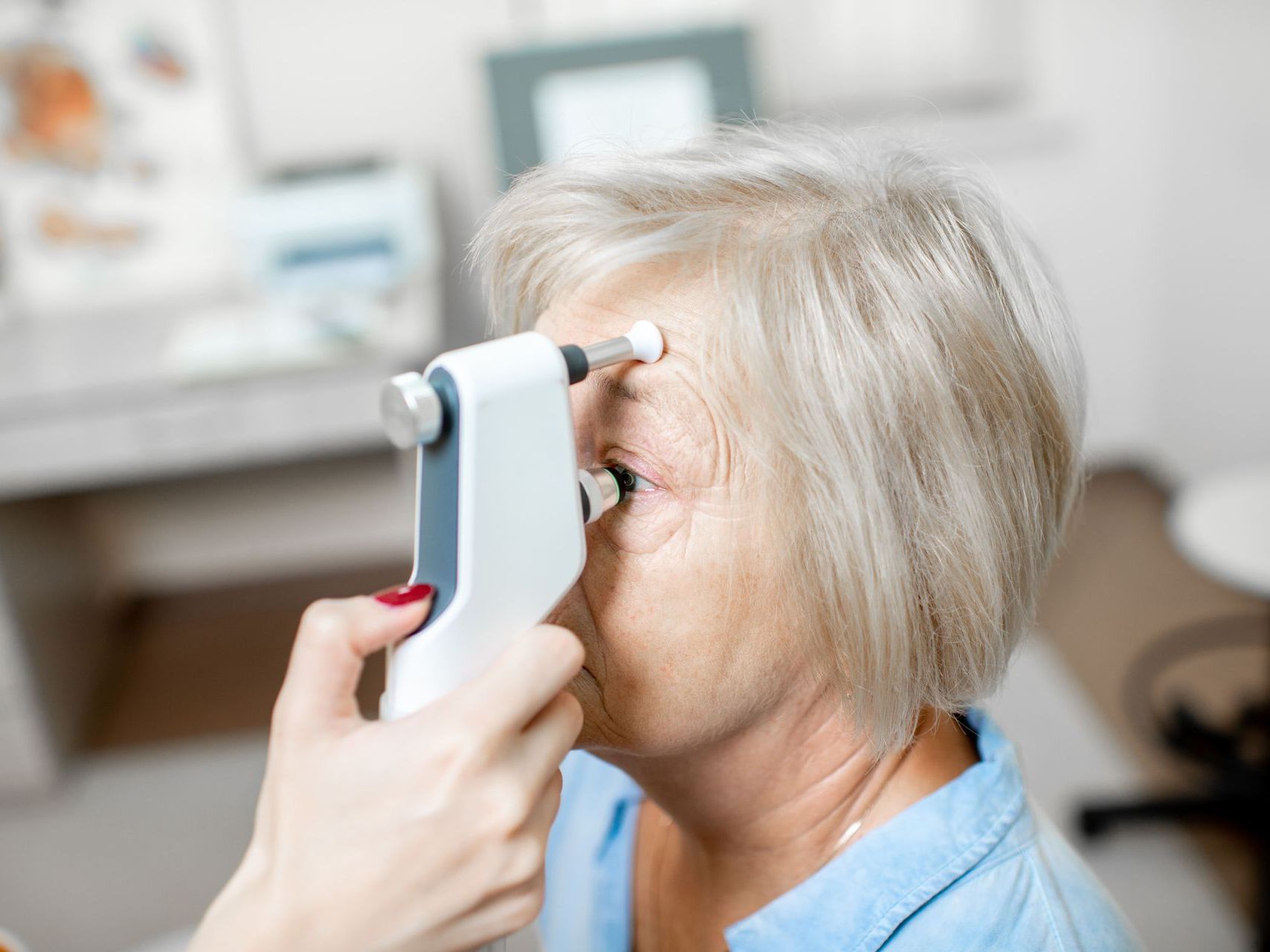 An image of an elderly woman is getting her eye pressure tested