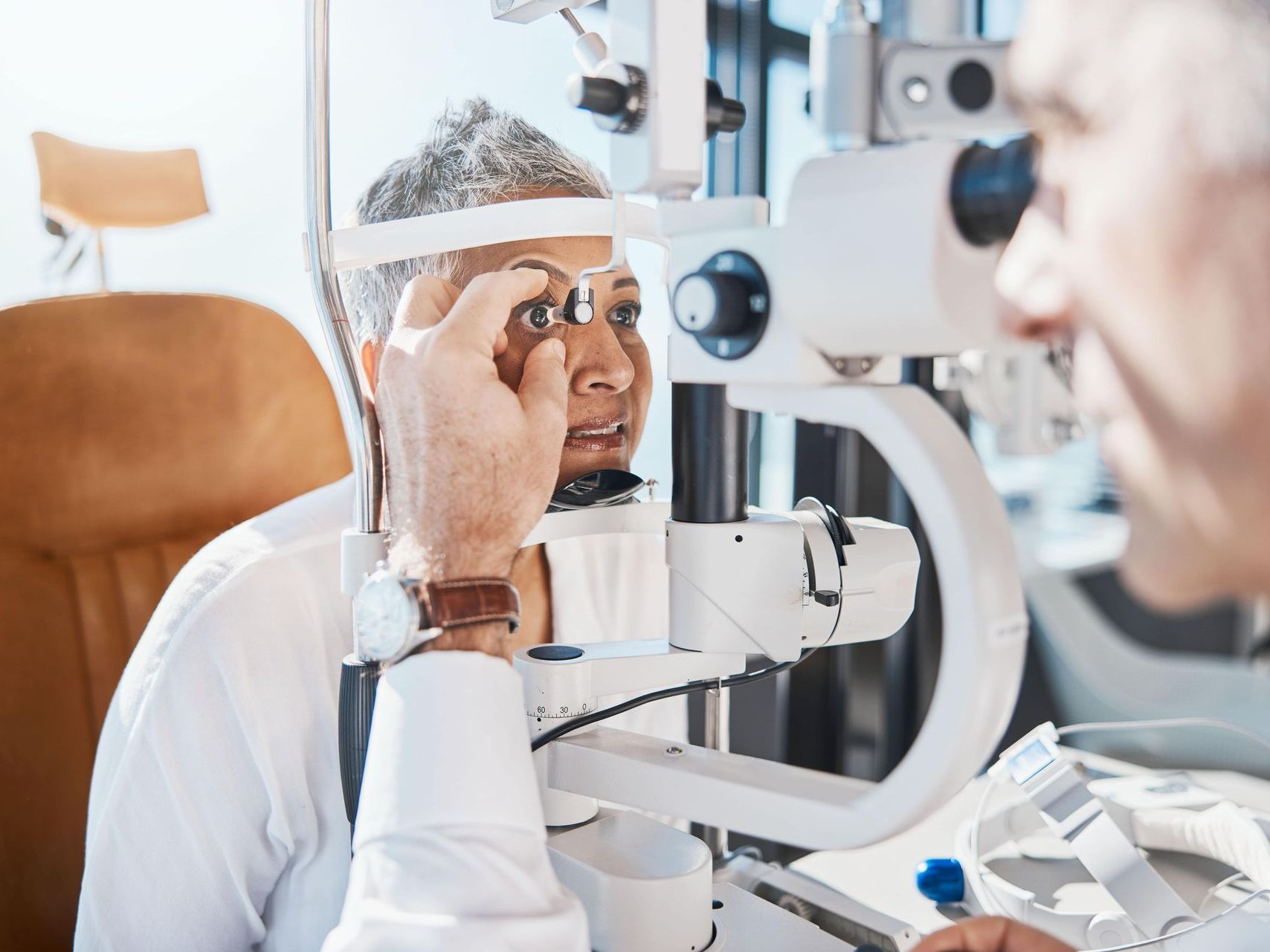 An image of a woman is getting her eyes examined by an ophthalmologist