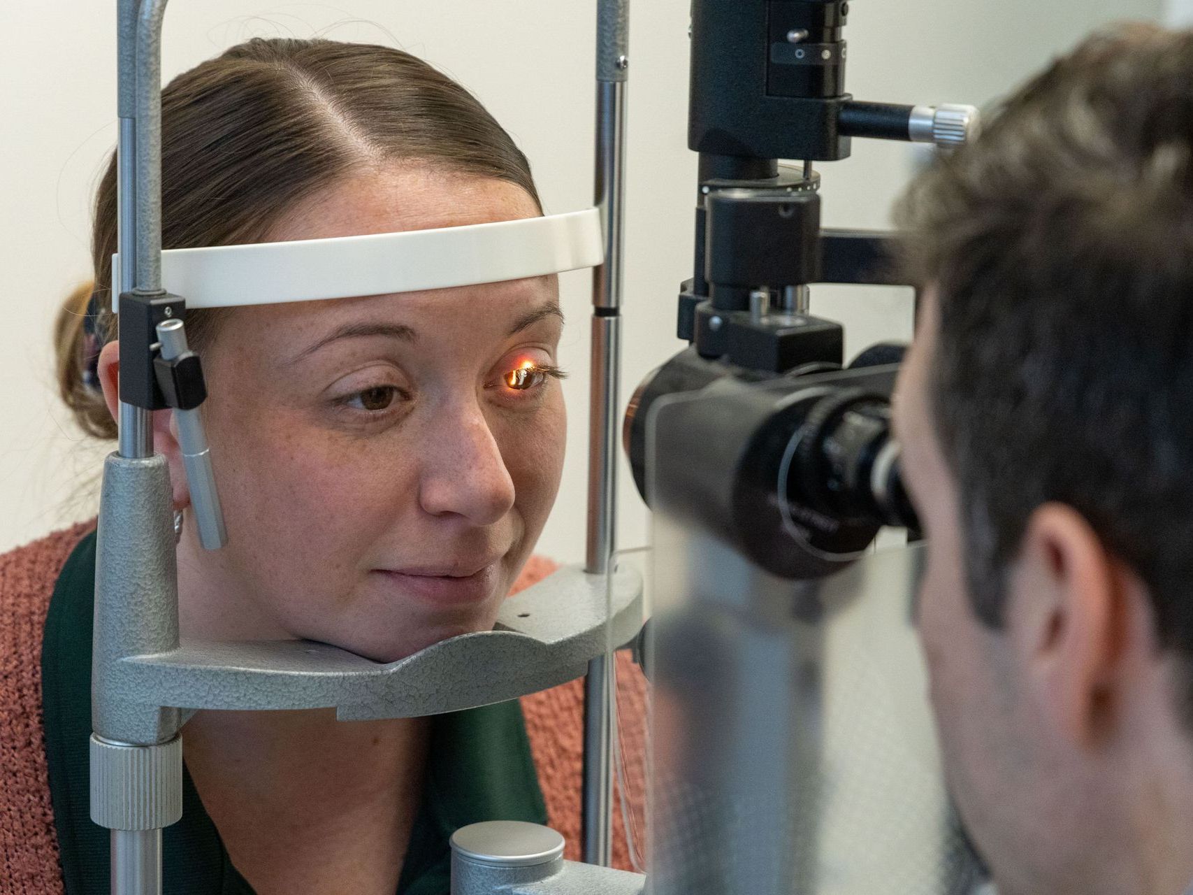 An image of a woman is getting her eyes examined by an ophthalmologist