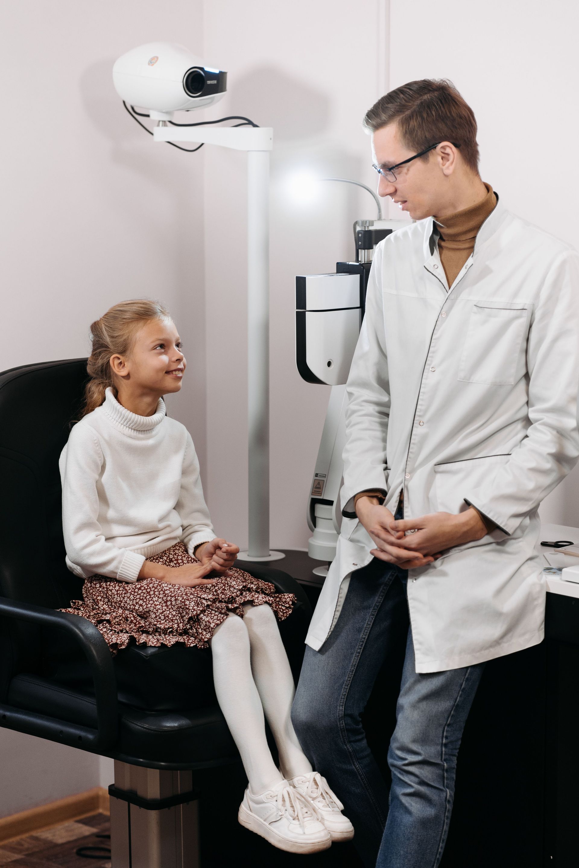 Doctor talking with smiling child in an eye exam room