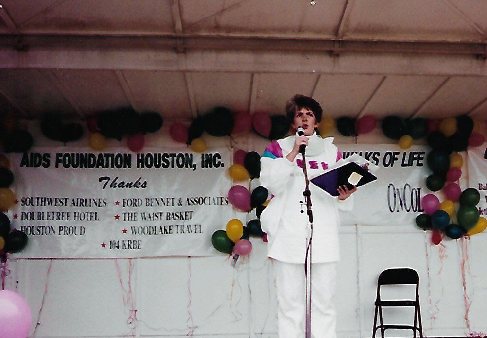 A man stands in front of a sign that says aids foundation houston inc.