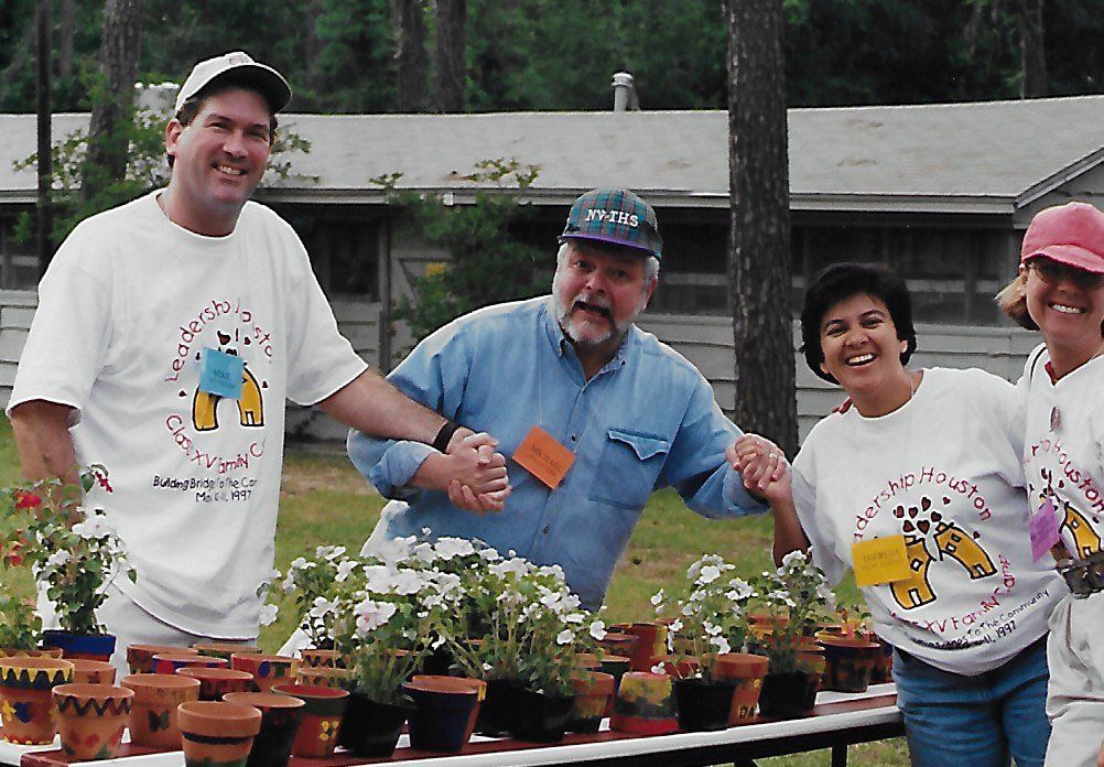 A group of people standing around a table with potted plants