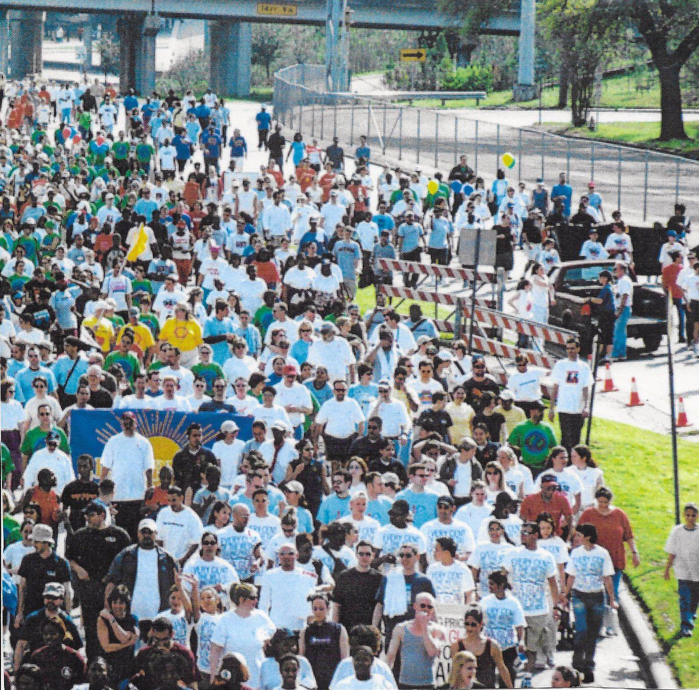 A large crowd of people walking down a street with a sign that says ' freedom ' on it