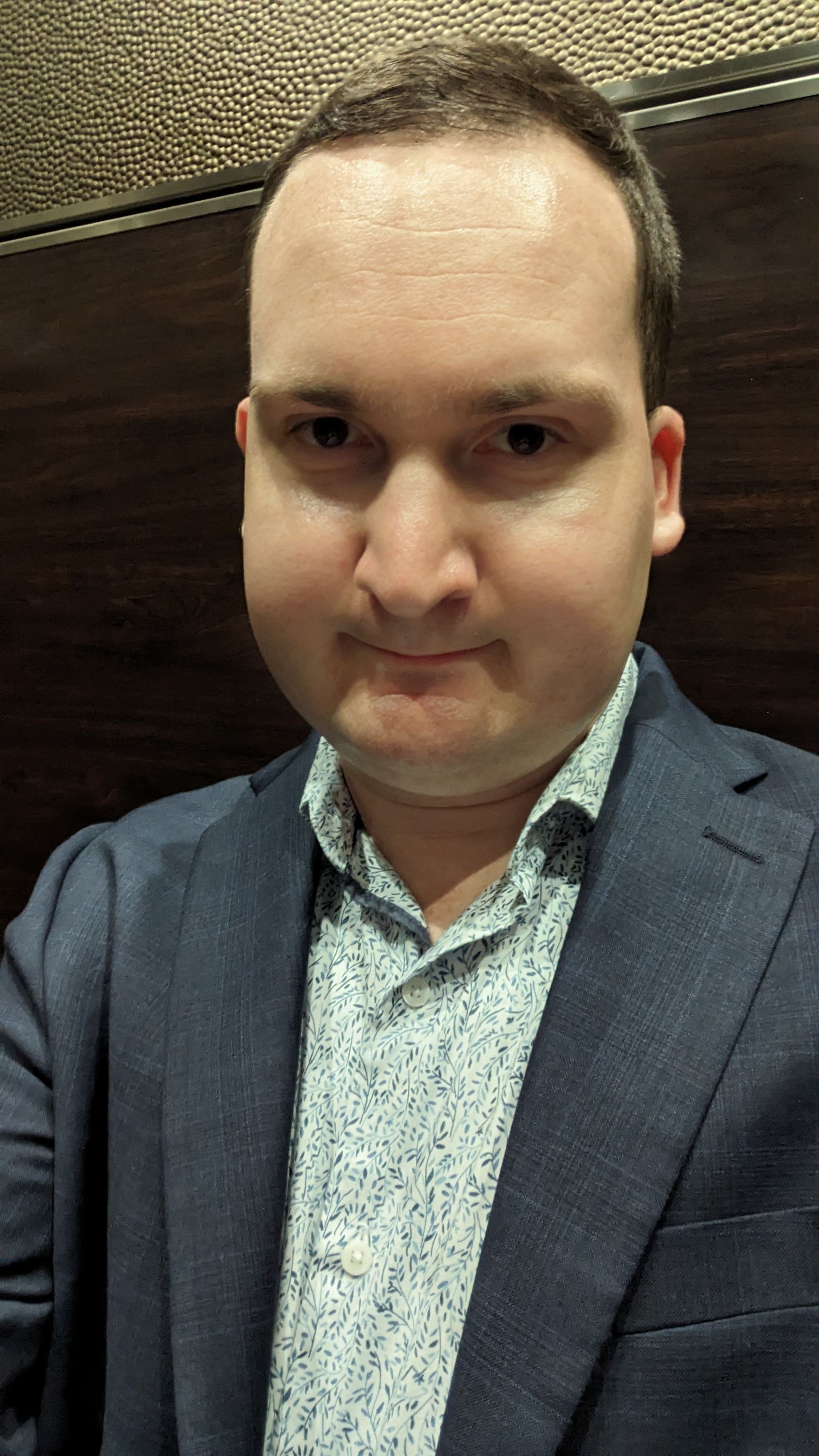 A man in a suit and shirt is taking a selfie.