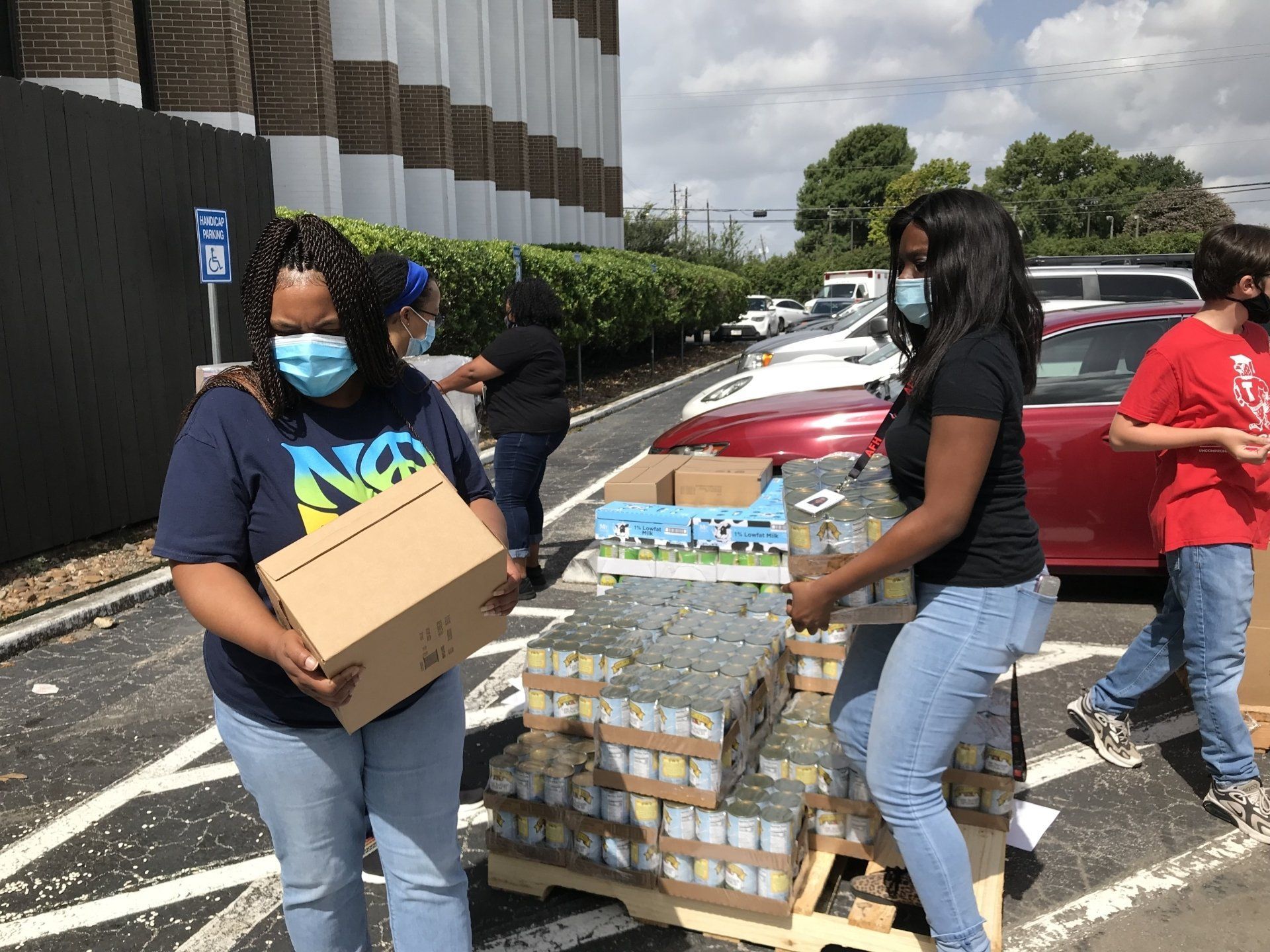 A group of people wearing face masks are loading cans onto a pallet.