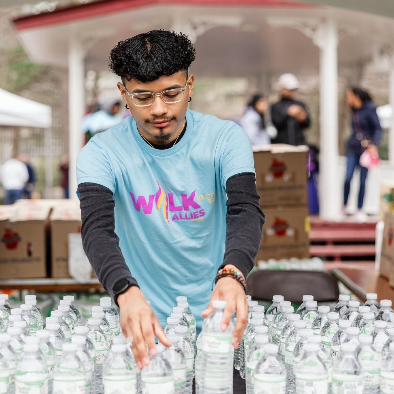 a masc-presenting AIH volunteer restocking water bottles at the Walk to End HIV 