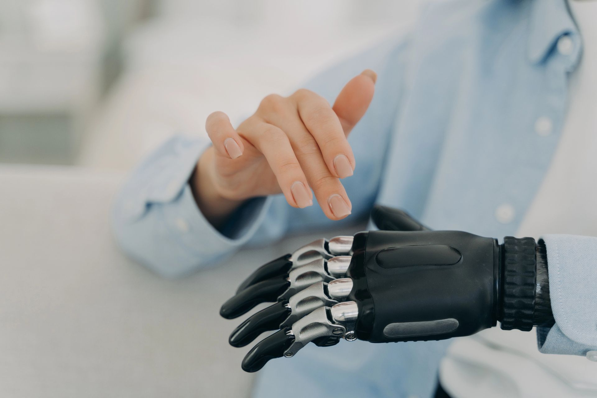 Una mano umana si protende verso una mano robotica in un ambiente d'ufficio illuminato.