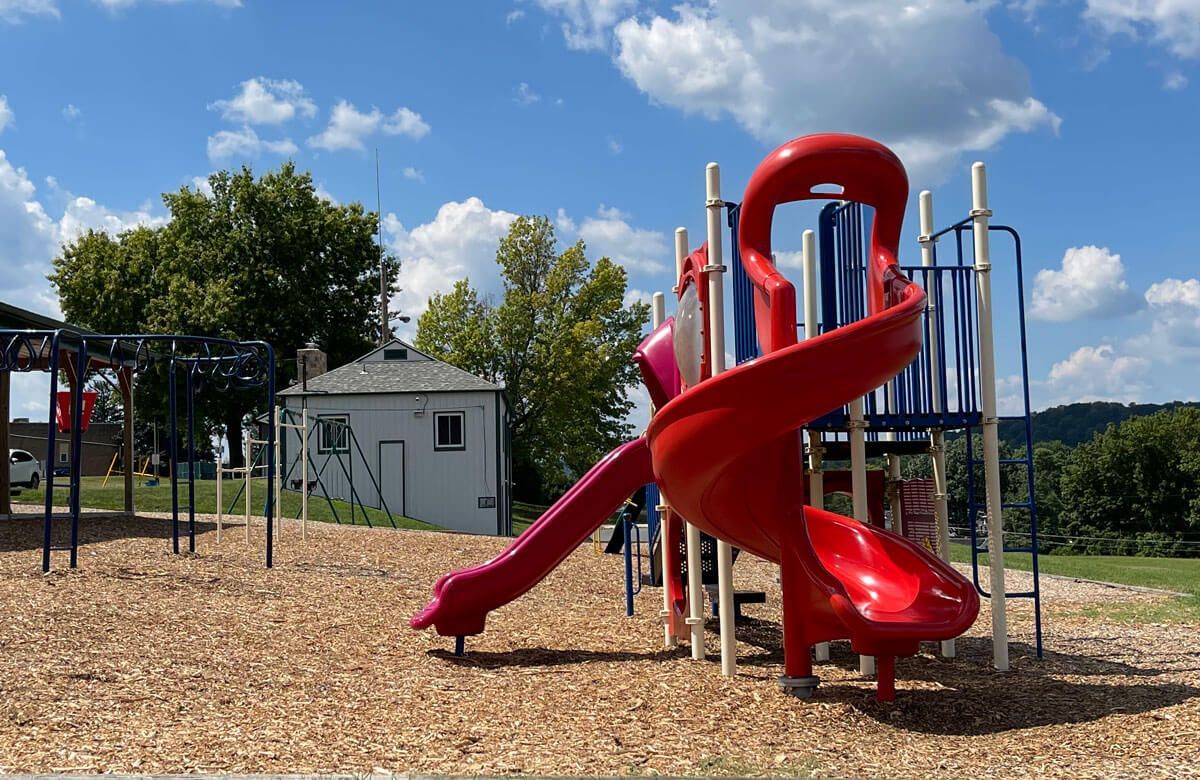 A red slide is in the middle of a playground.