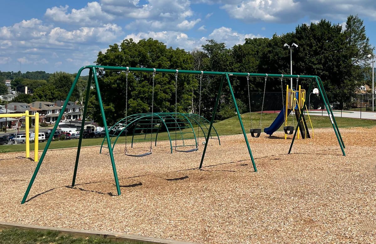 A playground with swings and a slide in a park.