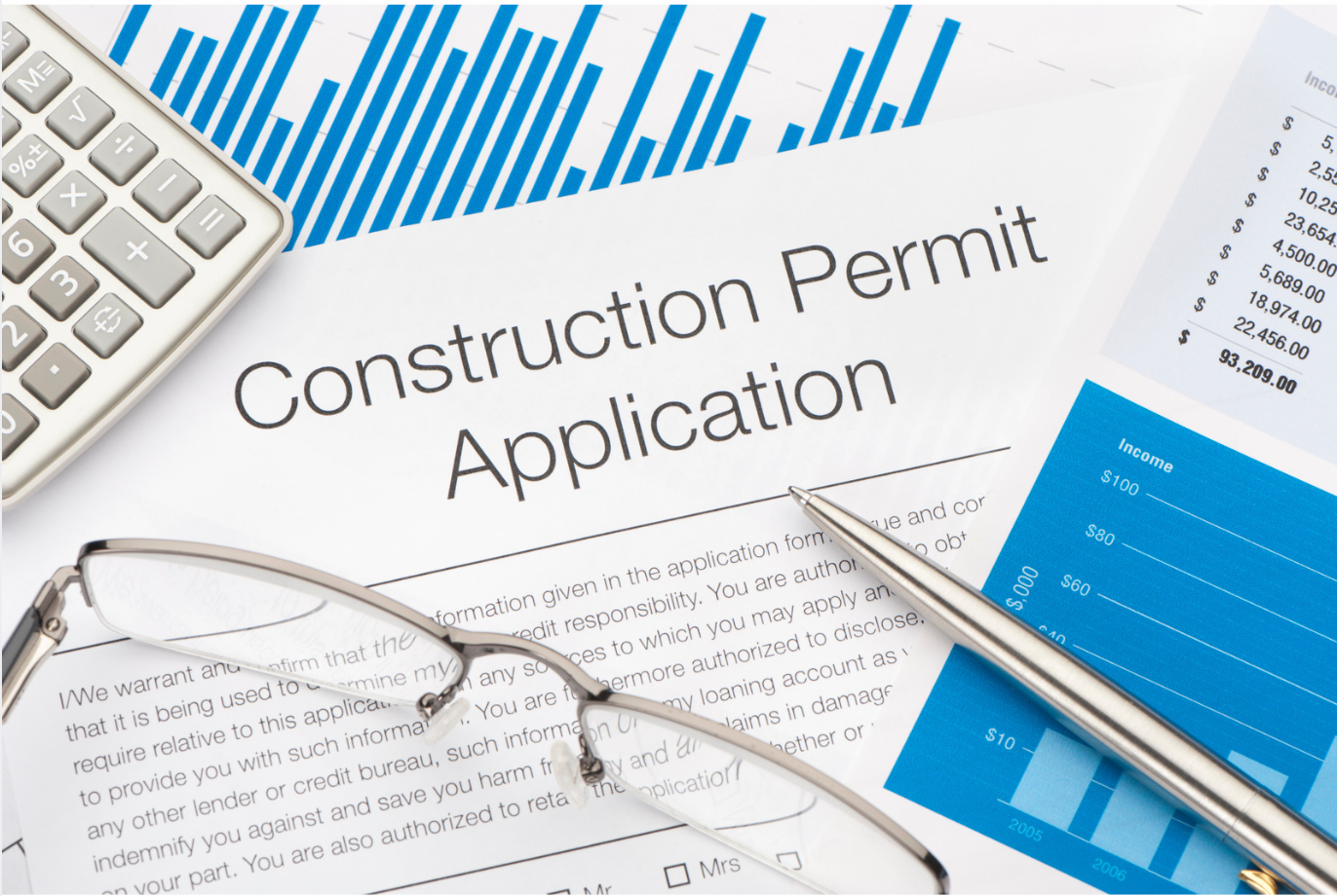 A construction permit application with a pen , calculator , and glasses.