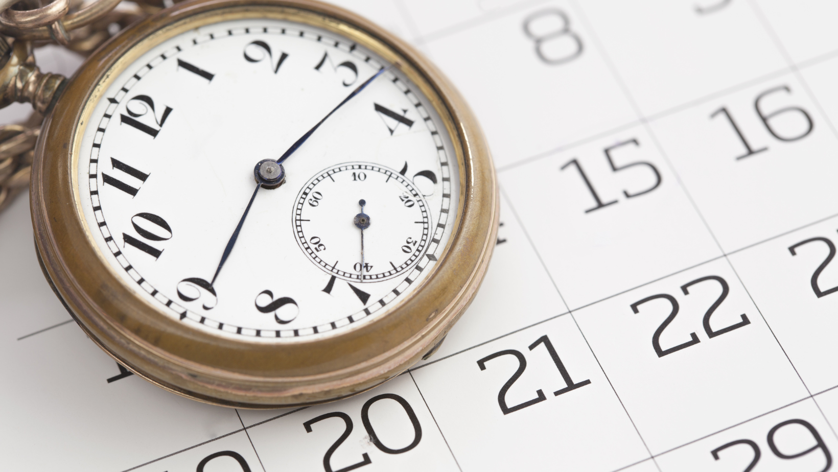 A pocket watch is sitting on top of a calendar.