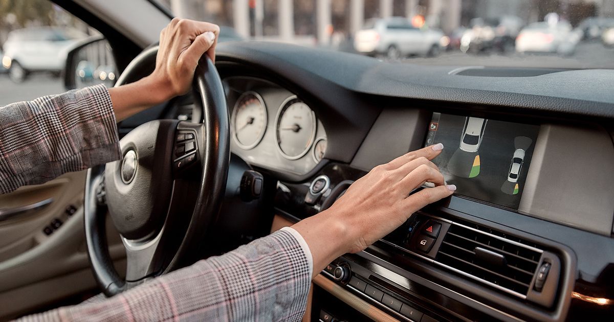 Driver hands steering wheel and infotainment controls in a modern car interior | European Autowerks – Virginia Beach