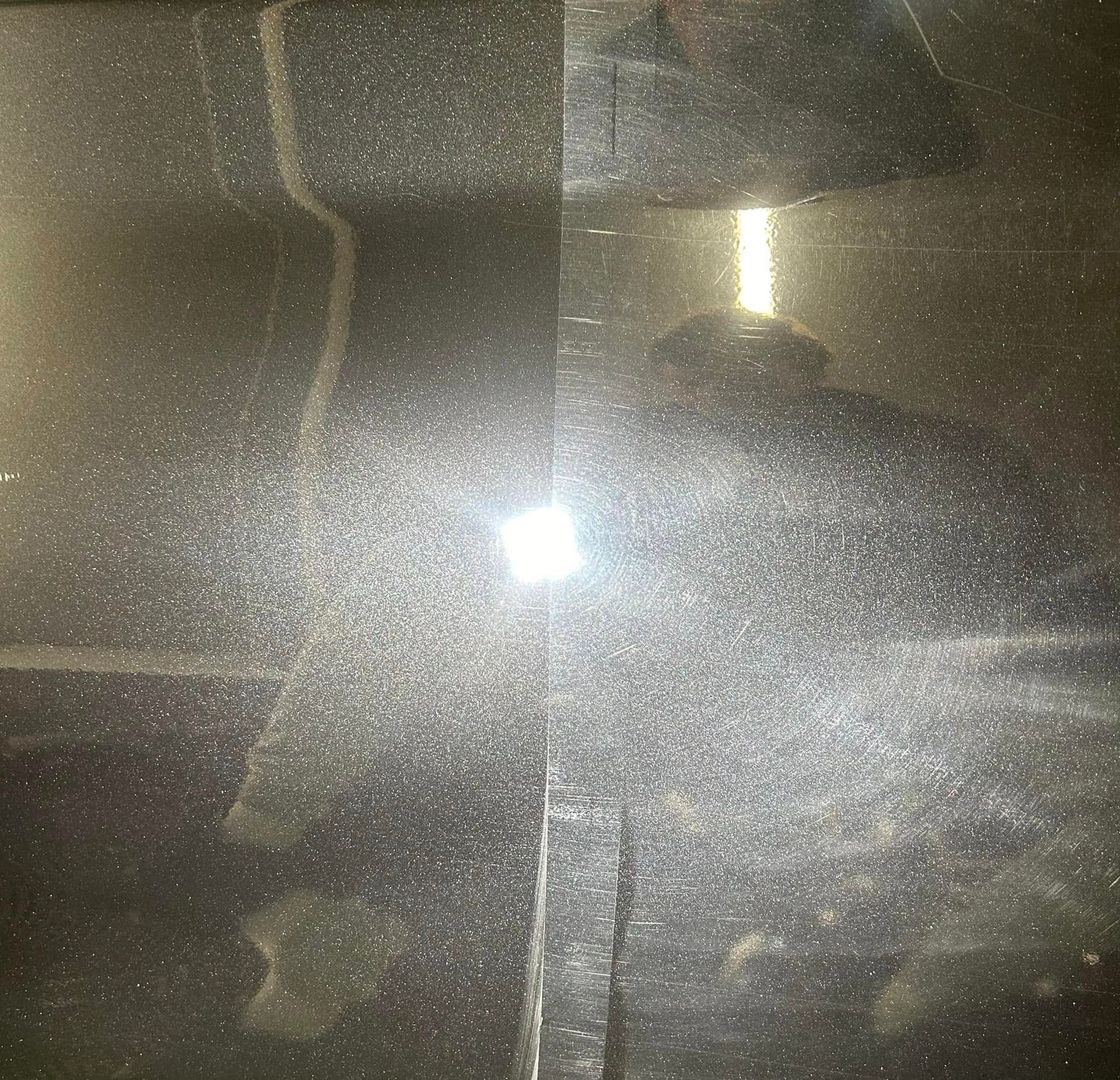 Machine polisher working on deep red paintwork showing before and after correction