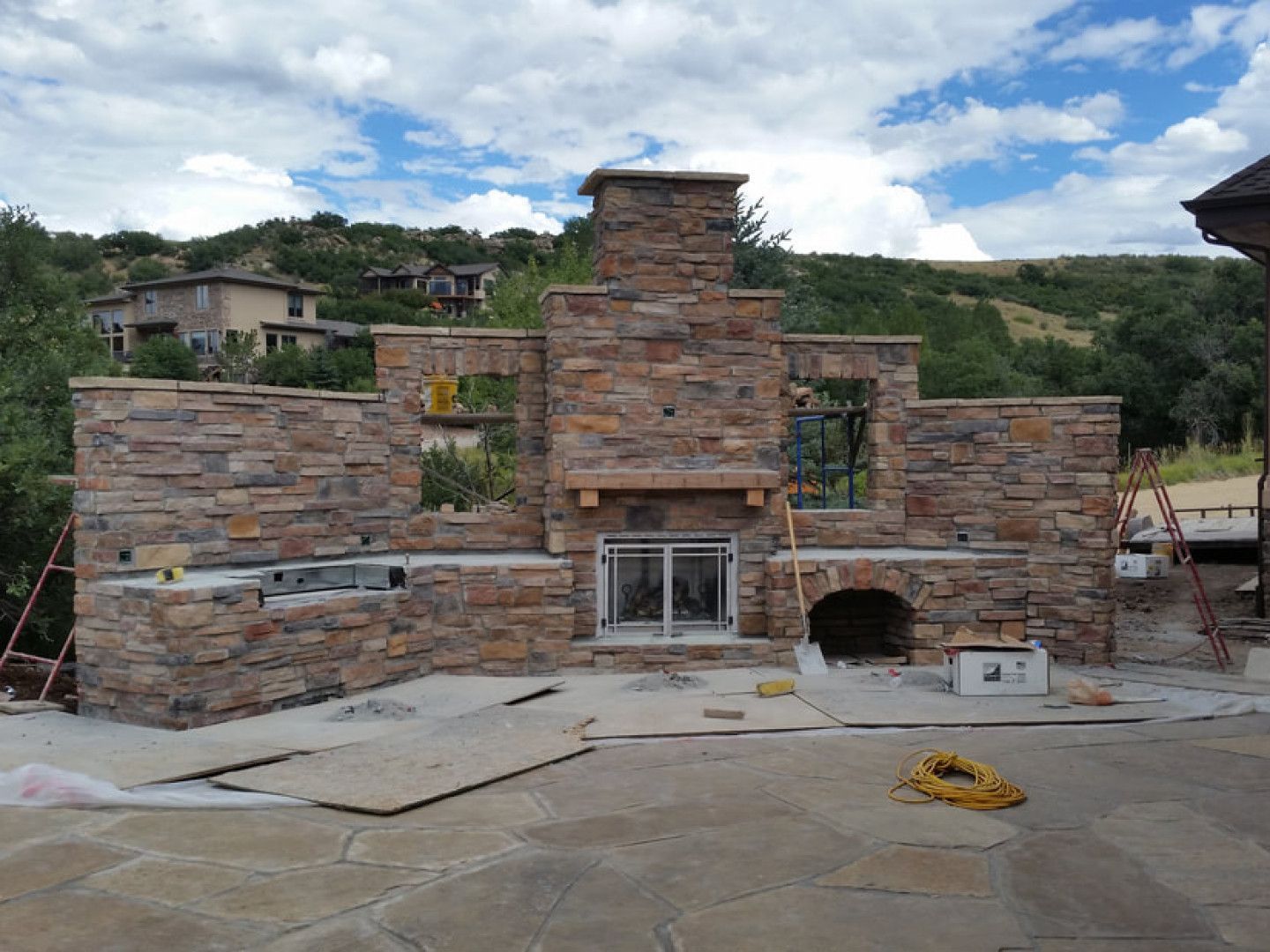 A stone fireplace is being built in the backyard of a house.