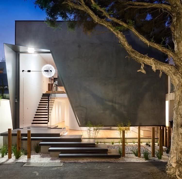 Modern House Exterior at Dusk With a Steep Dark Facade, Lit Entry Stairs — RYDALL BUILDING AND DEVELOPMENT in Freshwater, QLD