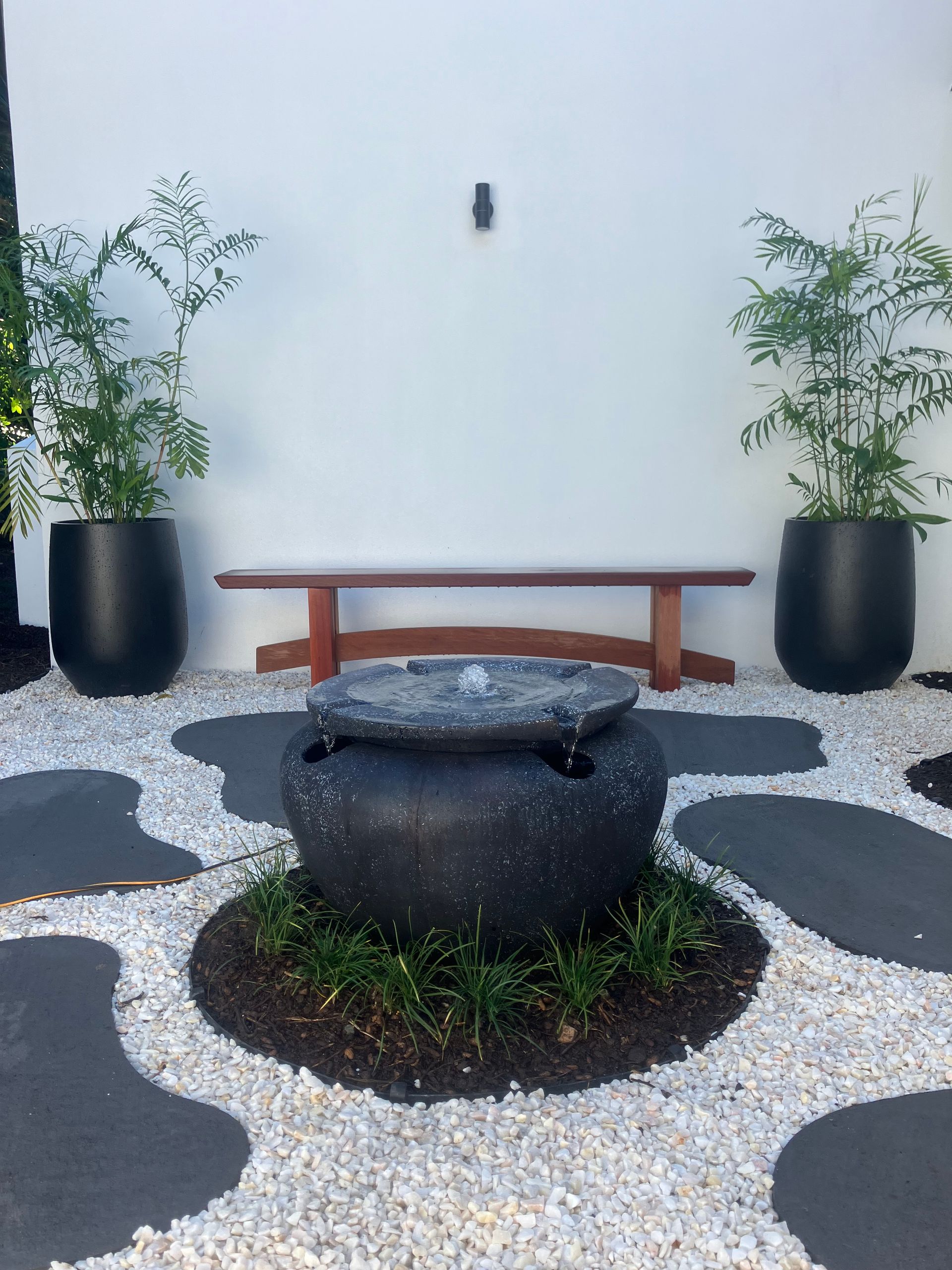 Modern Courtyard With a Fire Pit, Wooden Bench, and Potted Plants — RYDALL BUILDING AND DEVELOPMENT in Freshwater, QLD