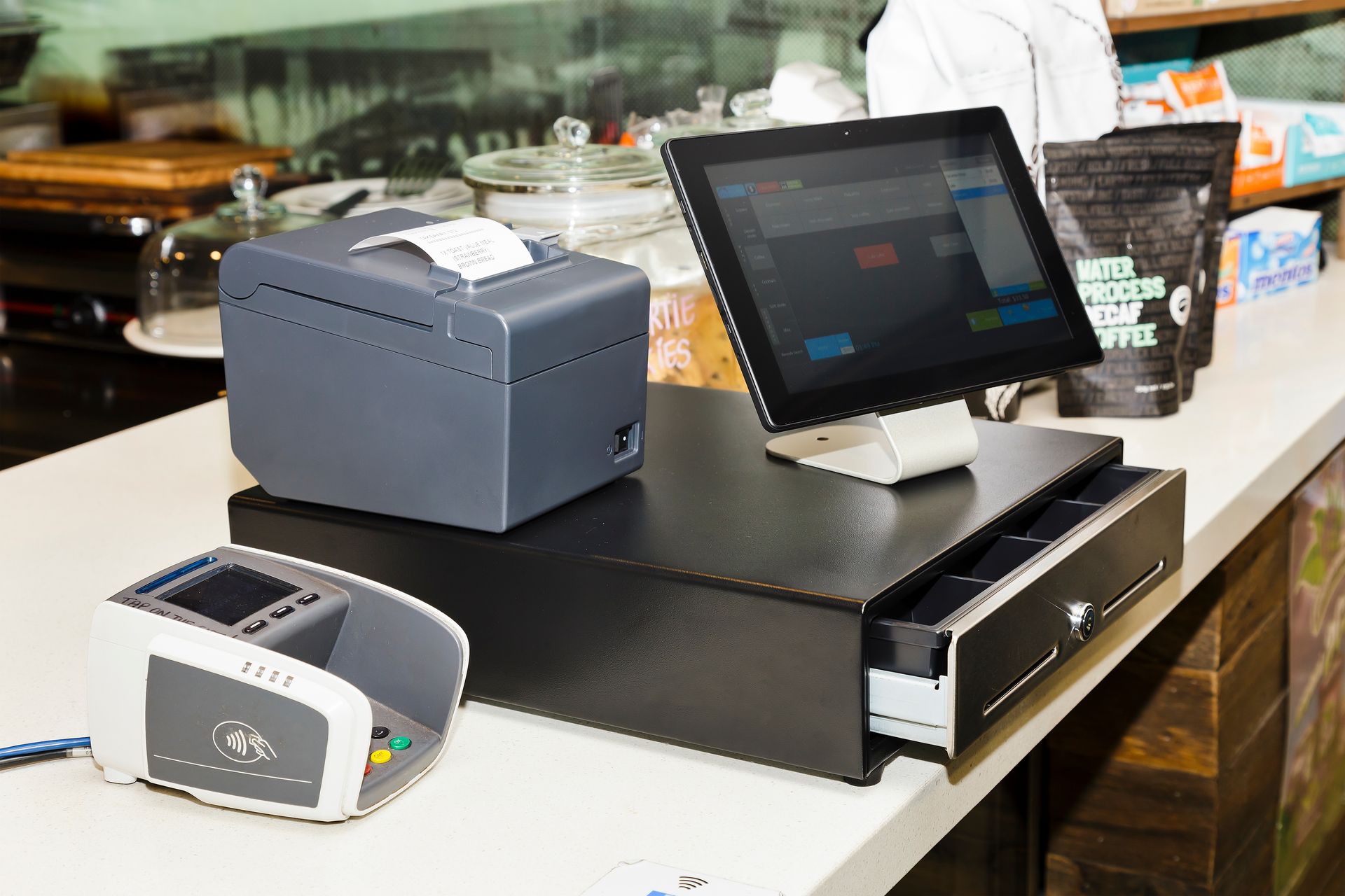 Point-of-sale checkout counter with touchscreen terminal, receipt printer, and card reader in a retail setting Point-of-sale checkout counter with touchscreen terminal, receipt printer, and card reader in a retail setting
